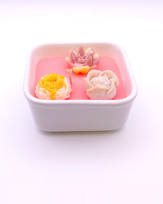 Vela floral rosa en recipiente cuadrado