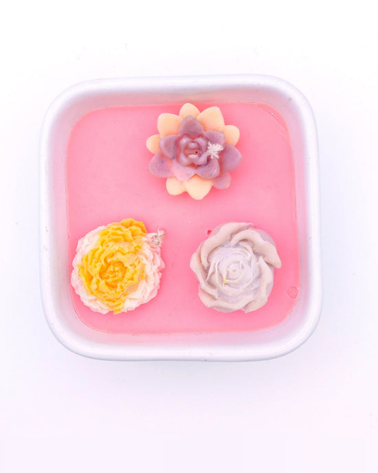 Vela floral rosa en recipiente cuadrado